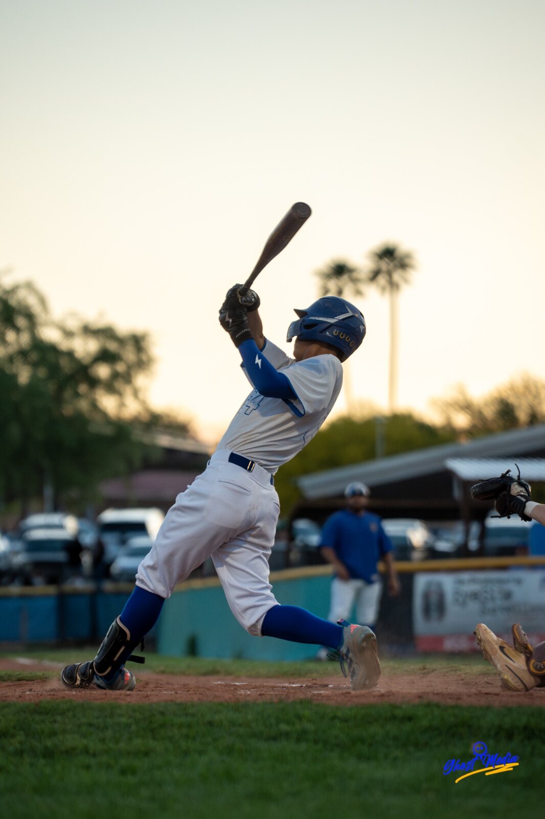 Baseball player swinging at sunset