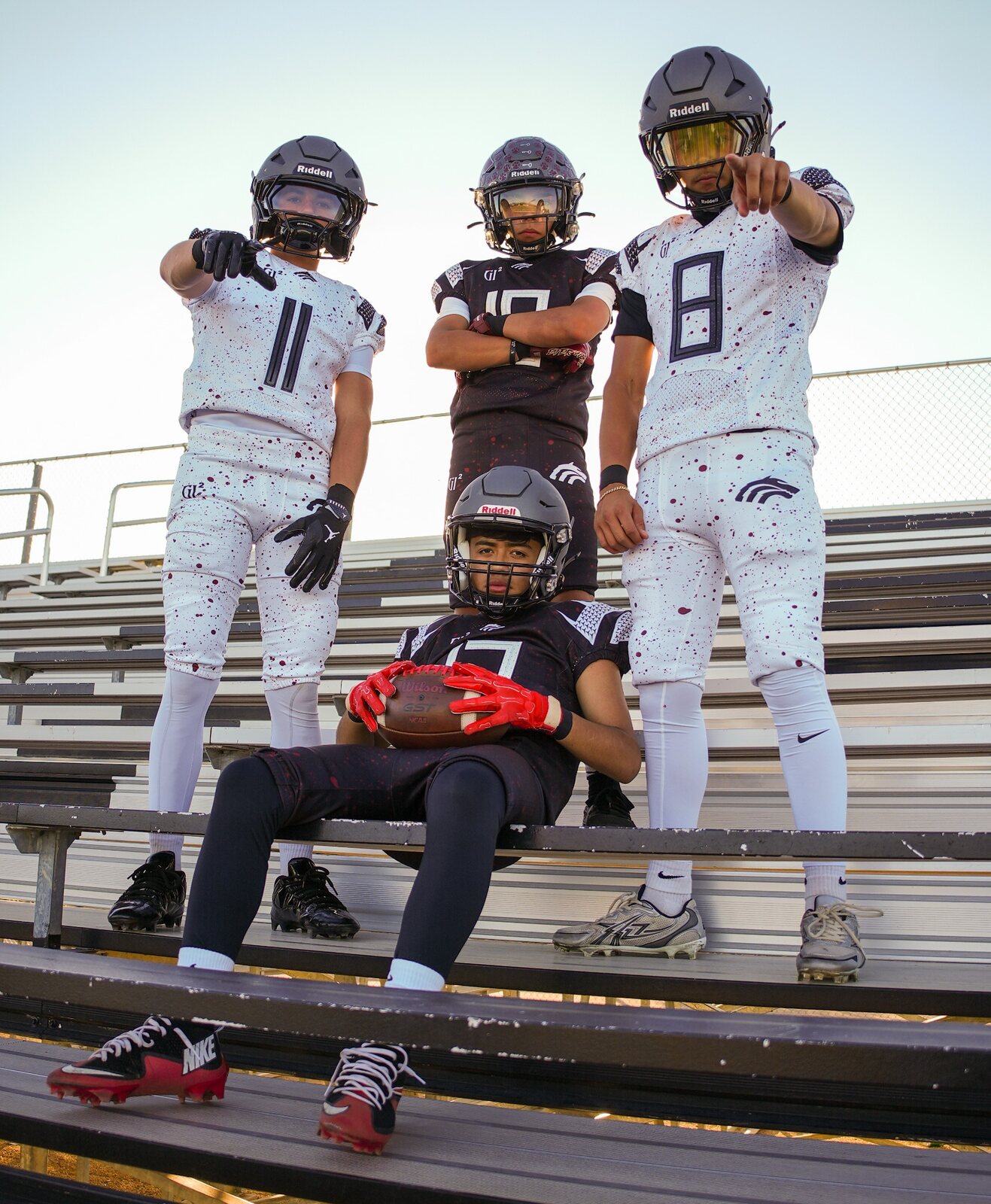 Four football players posing in stadium bleachers